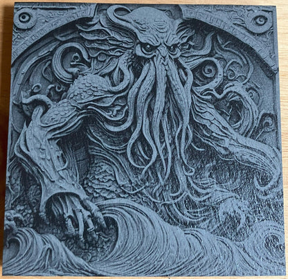 Square slate coaster engraved in 3D effect with Cthulhu rising from crashing waves, tentacles and claws spread