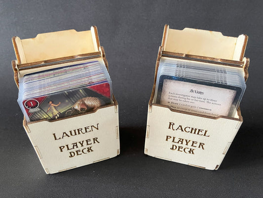 Two open natural wooden deck boxes holding Arkham Horror cards, engraved Lauren Player Deck and Rachel Player Deck