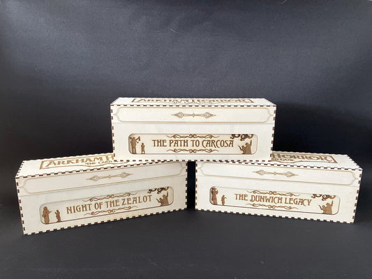 Three wooden card storage boxes engraved Night of the Zealot, The Path to Carcosa and The Dunwich Legacy