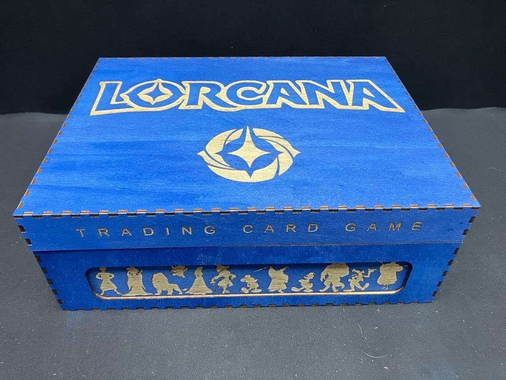 Blue wooden storage box with Lorcana logo and Trading Card Game engraved, plus a window of character silhouettes