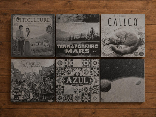 Six square slate coasters engraved with board game box art including Calico, Azul, Dune and Terraforming Mars