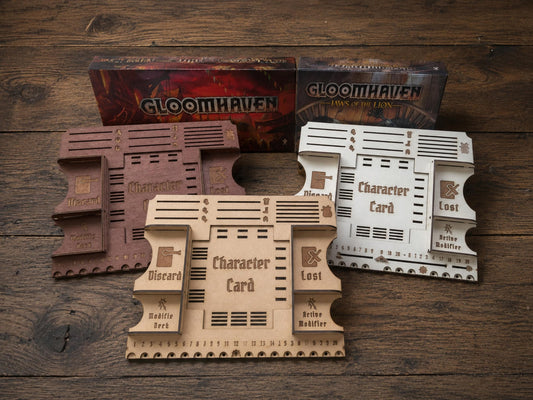 Three wooden player mat dashboards in brown, natural and white, with card slots and engraved symbols, before game boxes