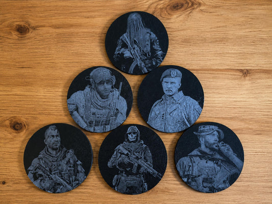 Six round black slate coasters engraved with soldier character portraits arranged on a wooden table