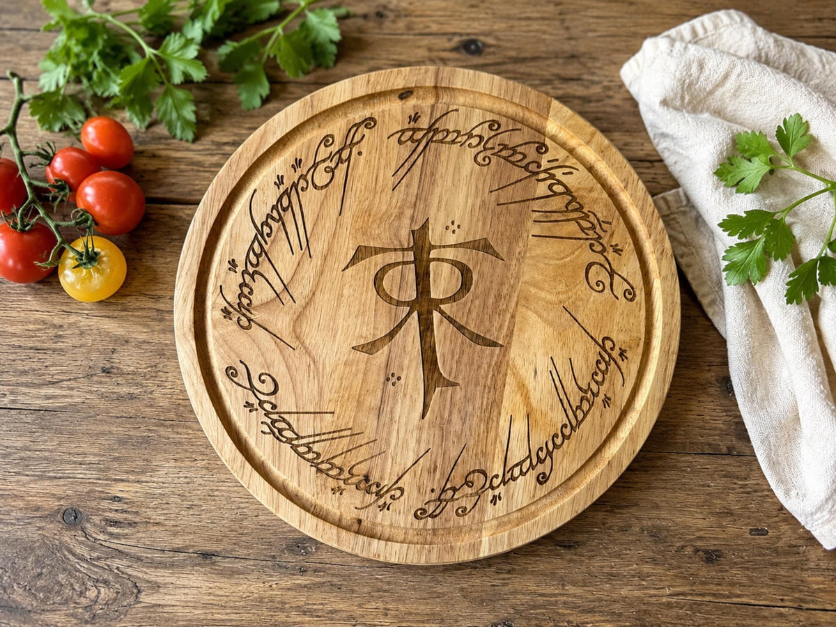 Round wooden chopping board engraved with the Tolkien monogram ringed by Elvish-style script, with tomatoes