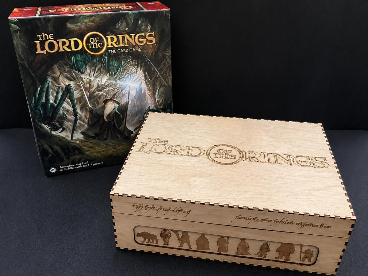 Natural wooden card storage box engraved with The Lord of the Rings title and character silhouettes, beside the card game box