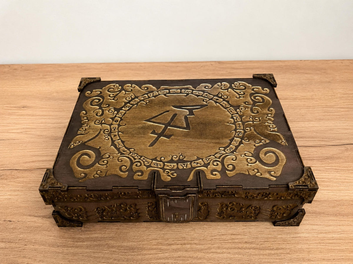 Dark stained wooden box with an ornate gold-toned engraved lid, central rune symbol and metal-look corner pieces