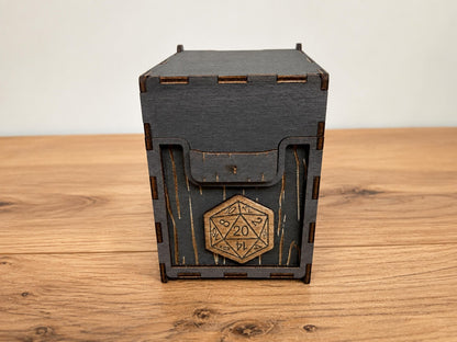 Grey wooden box with wood grain engraving, a d20 medallion on the front and integrated wooden hinges, on a wooden table