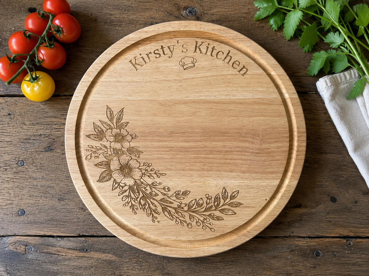 Round wooden board engraved Kirsty's Kitchen with a chef's hat and a floral spray, on a rustic table