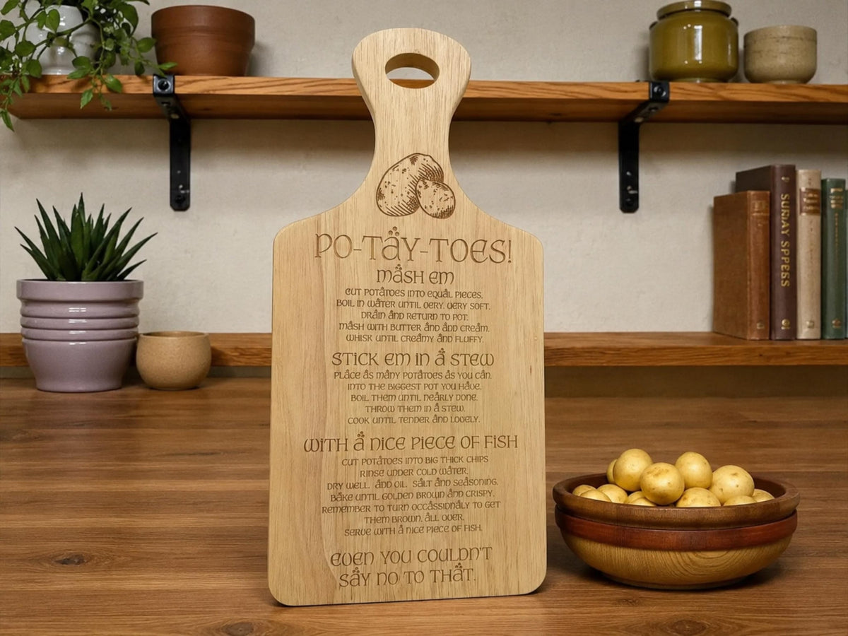 Wooden paddle board engraved Po-Tay-Toes with mash, stew and chips instructions, beside a bowl of potatoes